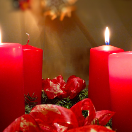 Adventskranz mit zwei brennenden und zwei nicht brennenden roten Kerzen, grüne Zweige, rotes Band