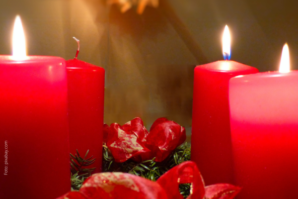 Adventskranz mit zwei brennenden und zwei nicht brennenden roten Kerzen, grüne Zweige, rotes Band